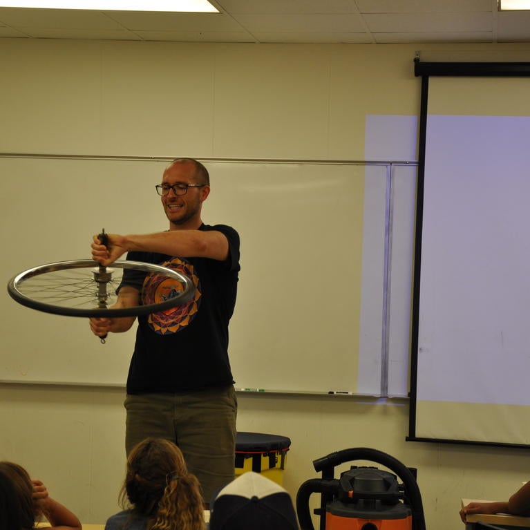 Standing on a turntable, Nathaniel Gabor explains angular momentum to his young audience. (I. Pittalwala/UCR)